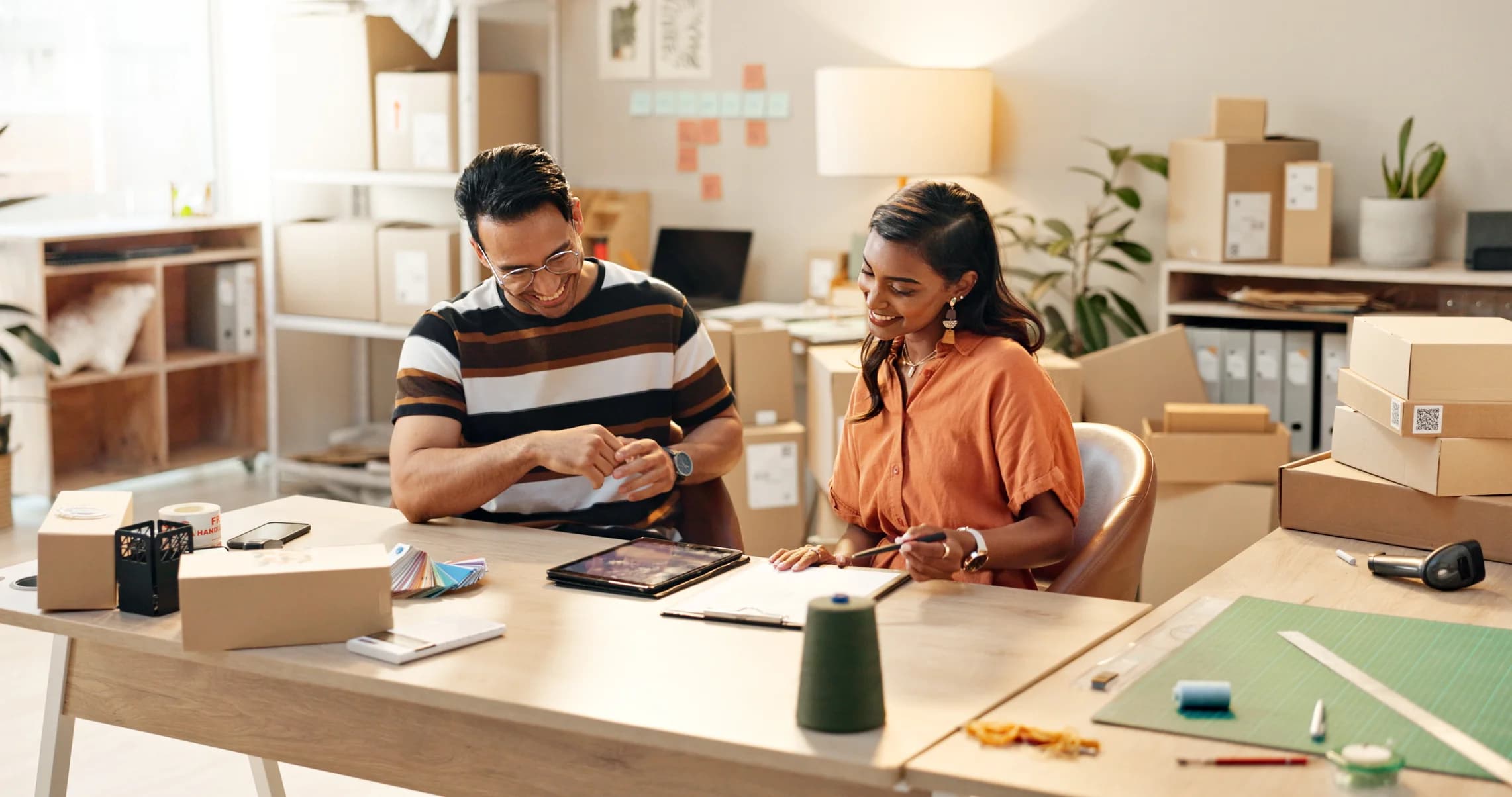 Two colleagues smiling while reviewing their business finances at a desk